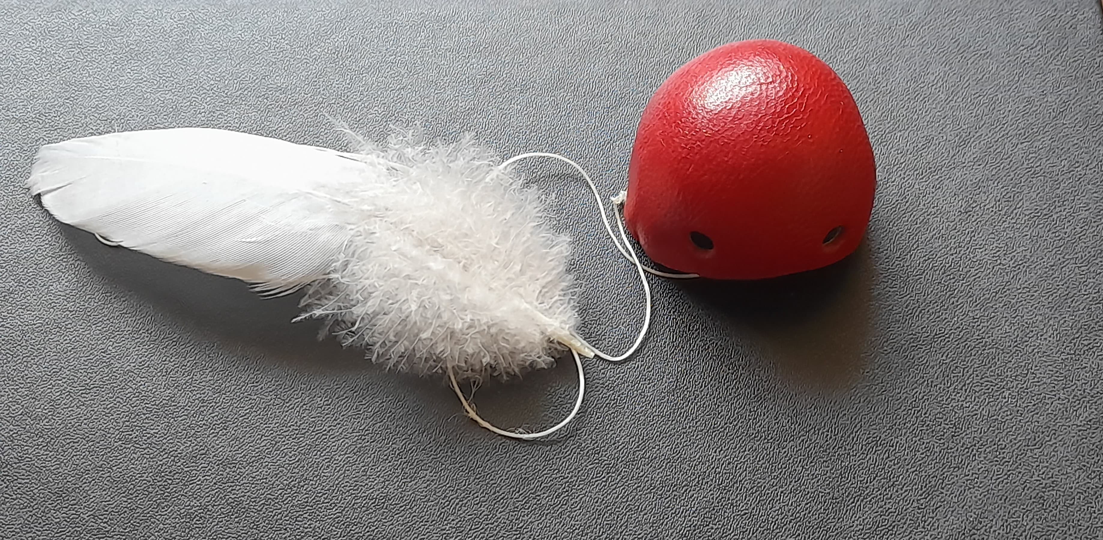Rote Clownsnase neben einer weißen Feder